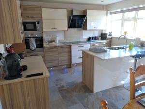 a kitchen with white cabinets and a counter top at Smitten House 4 Bedroom RHYL in Rhyl