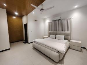 a white bedroom with a bed and a ceiling at Evergreen Lodge - Unmarried couples are not allowed in Rawalpindi
