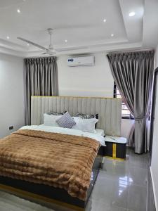 een slaapkamer met een groot bed en een bruine deken bij The 8 Luxury Apartments in Accra