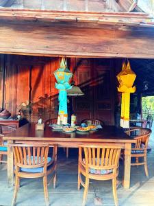 a wooden table with chairs and a table with lights at Teak House Homestay I in Ban Thung Satong