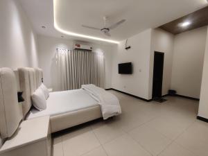 a white room with a bed and a television at Evergreen Lodge - Unmarried couples are not allowed in Rawalpindi