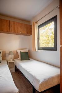 two beds in a small room with a window at Rives d'Arc in Vallon-Pont-dʼArc