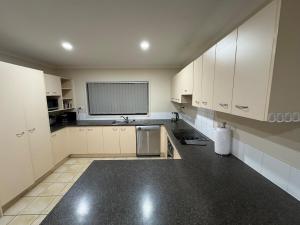 a kitchen with white cabinets and a sink and a window at Relaxing 3BR Home by Wattle Downs Reserve in Auckland +12 photos