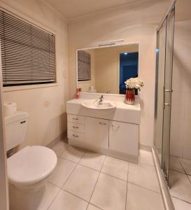 a white bathroom with a toilet and a sink at Relaxing 3BR Home by Wattle Downs Reserve in Auckland