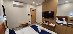 a hotel room with a bed and a flat screen tv at Hotel Earth Orbit in Gandhinagar