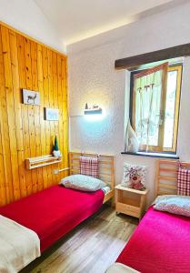 two beds in a room with wood paneling at ALLA CASCATA in centro Branzi self check-in parcheggio gratuito coperto in Branzi
