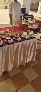 a person standing next to a table with plates of food at STERLEON HOTEL RIVERSIDE in Nairobi +5 photos