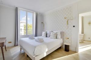 Un dormitorio blanco con una cama grande y una ventana. en Pick A Flat's Apartment in Grands-Boulevards - Boulevard Saint-Denis, en París