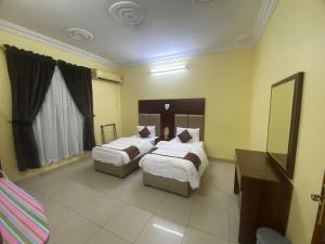 a hotel room with two beds and a mirror at العييري للشقق المخدومة المدينة 3 in Al Madinah