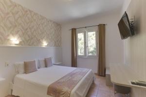 een slaapkamer met een wit bed en een raam bij Hotel des Etrangers in Bonifacio