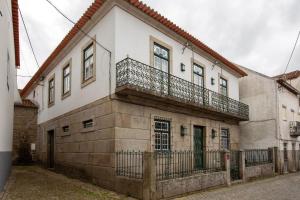 a building with a balcony on the side of it at Casa dos Livros - Guest House in Vila Nova de Tazem