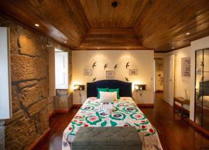 a bedroom with a bed and a stone wall at Casa dos Livros - Guest House in Vila Nova de Tazem