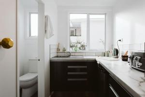 a white kitchen with a sink and a toilet at Surf's Up - pet-friendly Fitzroy lifestyle home in New Plymouth