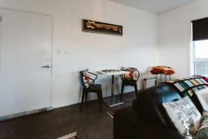 a living room with a couch and a table with chairs at Surf's Up - pet-friendly Fitzroy lifestyle home in New Plymouth +8 photos