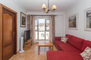 a living room with a red couch and a tv at 3BR Buddha Penthouse - Solarium & Pool in Sardina