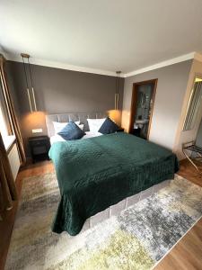 a bedroom with a large bed with a green blanket at Hotel Garni BALTICpetite in Heringsdorf