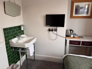 ein Badezimmer mit Waschbecken und einem Fernseher an der Wand in der Unterkunft Regency Guest House in Cambridge + 36 Fotos