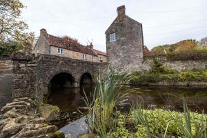 an old stone bridge over a river with a building at The Old Loft House in Chew Stoke in Chew Stoke
