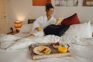 a woman sitting on a bed with a tray of food at The Spot - Luxurious 3-Bedroom Apartment in the Heart of Winnipeg in Tuxedo