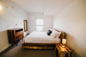 a bedroom with a bed and a dresser and a table at The Spot - Luxurious 3-Bedroom Apartment in the Heart of Winnipeg in Tuxedo
