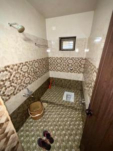 a bathroom with a shower with a toilet and some sandals at Lenzo Home Stays in Kāsaragod +13 photos