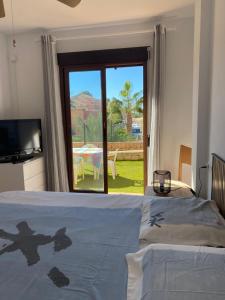 een slaapkamer met een bed en uitzicht op een patio bij Beautiful apartment with gardens - sea and mountain views in Isla Plana +24 foto's