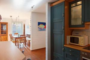 a kitchen and dining room with blue cabinets and a microwave at Ferienwohnung Merkel in Koserow