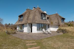 een rieten huis met stoelen en een terras bij Seaside in Klappholttal