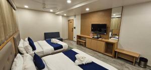 a hotel room with two beds and a television at Hotel Earth Orbit in Gandhinagar