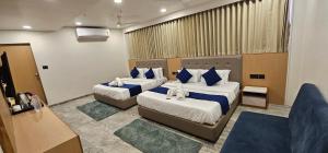 a hotel room with two beds with blue pillows at Hotel Earth Orbit in Gandhinagar