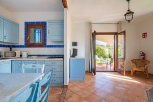 a kitchen with blue cabinets and a door leading to a patio at Vecchio Stazzo in San Teodoro +102 photos