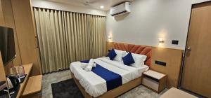 a bedroom with a large bed with blue and white pillows at Hotel Earth Orbit in Gandhinagar
