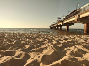a sandy beach with a pier in the water at Gryfhaus - Pokój Bosmański, kameralny, 22 m2, parking, Wi-Fi, blisko morza, wysoka ocena 9,9 in Międzyzdroje