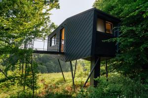 a black house on poles in a field with trees at Oak - K1 Baumhaus in Odenthal +14 photos