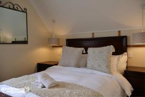 a bedroom with a white bed with pillows and a mirror at Amber & Birch in Dullstroom