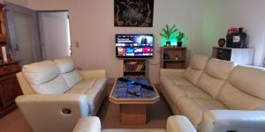 a living room with two white couches and a tv at Ganze 95qm Wohnung mit 4 Schlafzimmern, privater Komfort Küche, Bad, WC und Wohnzimmer, mit Gratis Frühstück und Parkplatz, mit Garten, so privat wie zu Hause in Kassel