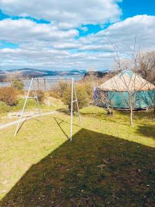 a swing set in a field with a tent at A Magical Cosy Garden Yurt in Ladyʼs Odell