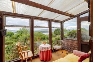 eine abgeschirmte Veranda mit einem Tisch und Stühlen in der Unterkunft Serene Bantry Bay Cabin Retreat in Ladyʼs Odell