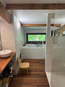 een badkamer met een bad, een wastafel en een stoel bij Gîte du Séquoia - Paisible maison de campagne in Vallet