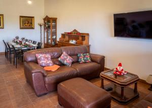 a living room with a brown leather couch and a table at Stunning 18th century cortijo with 2 private pools sleeps 12 in Vera