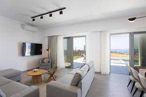 a living room with a couch and a tv and a table at MiNo Mare modern Sea View Villa with Pool up to 12 in Panormos Rethymno
