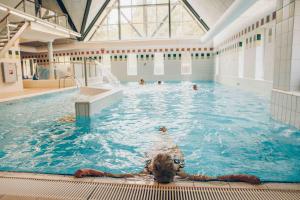 a group of people swimming in a swimming pool at Zandduin Wellness Villa | 10 personen in Hooghalen