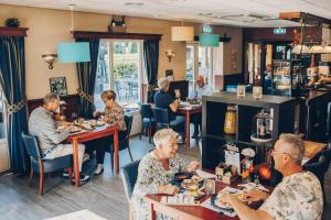 a group of people sitting at tables in a restaurant at Zandduin Wellness Villa | 10 personen in Hooghalen