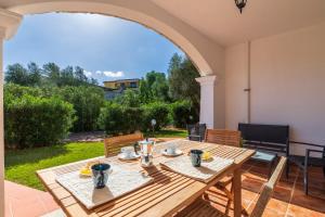 a wooden table in a patio with an archway at Vecchio Stazzo in San Teodoro