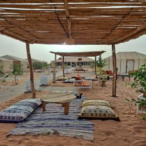 a patio with pillows and a table and a tent at Desert Paradise Luxury Camp in Merzouga