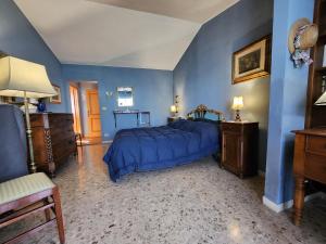 een slaapkamer met blauwe muren en een bed met een blauwe sprei bij Argentario Rooms - By The Sea in Porto Santo Stefano