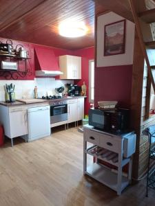 eine Küche mit weißen Schränken und roten Wänden in der Unterkunft Une maison chaleureuse et accueillante au cœur de la Chartreuse in Saint-Pierre-dʼEntremont