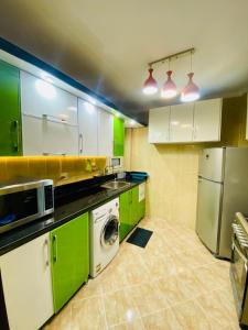 a kitchen with green and white cabinets and a dishwasher at شقه المتحف in Ghaţāţī