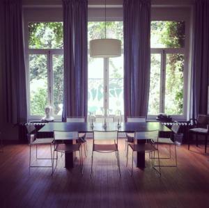 a dining room with a table and chairs and windows at Maison Flagey Brussels in Brussels