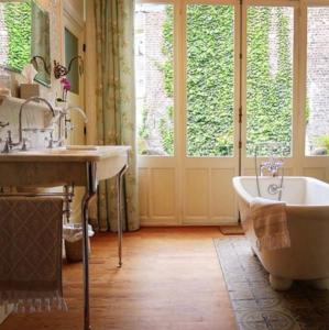 
a bath tub sitting next to a window in a bathroom at Maison Flagey Brussels in Brussels
